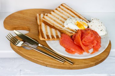 Kahvaltı menüsü: kızarmış ekmek, füme somon, haşlanmış yumurta ve beyaz pencere eşiğinde bir fincan kahve.