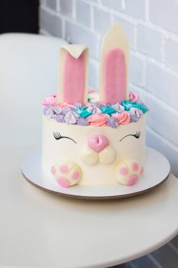 Çocukların doğum günü için şirin tavşanlı beyaz ve pembe pasta. Şekerleme ve kremadan yapılmış bir tavşan. Beyaz arkaplan.