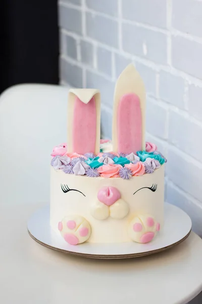 Torta blanca y rosa con lindo conejito para cumpleaños de niños. Conejito hecho de fondant y crema de mantequilla. Fondo blanco . Fotos de stock libres de derechos
