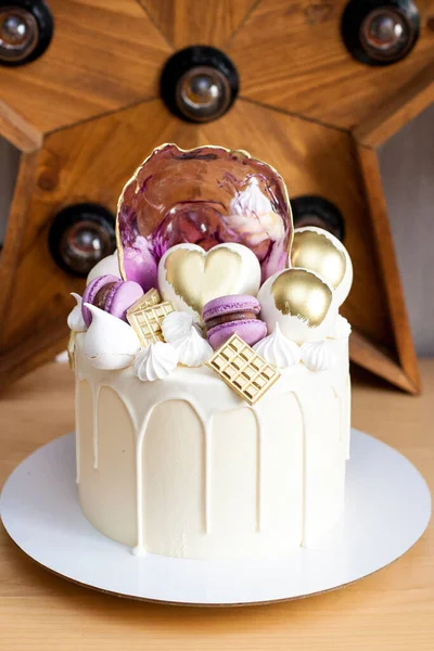 Bolo elegante moderno com chocolate branco derretido, coração dourado e bolas de chocolate, macaroons, merengue e caramelo . — Fotografia de Stock