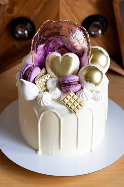 Bolo elegante moderno com chocolate branco derretido, coração dourado e bolas de chocolate, macaroons, merengue e caramelo . — Fotografia de Stock