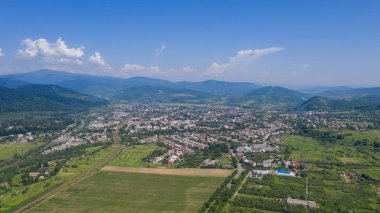 Karpatya dağlarındaki Svalyava 'nın havadan görünüşü. Geometrik desenli doğal arka plan - tarlaların bej ve kırmızı dikdörtgenleri ve çatılar ve yollar ve ağaçlar. Zakarpattia, Ukrayna.