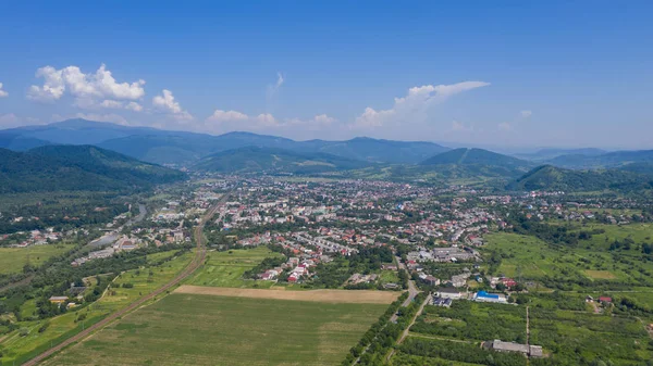 Karpatya dağlarındaki Svalyava 'nın havadan görünüşü. Geometrik desenli doğal arka plan - tarlaların bej ve kırmızı dikdörtgenleri ve çatılar ve yollar ve ağaçlar. Zakarpattia, Ukrayna.