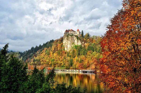 Красочный Блед осенью, на заднем плане - замок на вершине скалы. Словения — стоковое фото