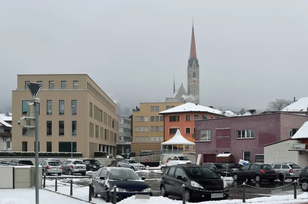 圣洛朗尤斯新教区教堂 - 列支敦士登舍安-瓦杜兹。城市街道的碎片。背景 - 阿尔卑斯山的白雪覆盖的山峰. — 图库照片