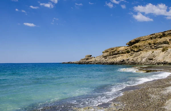 Berrak mavi suları, küçük çakıl taşları ve kumları olan tenha bir sahil.,