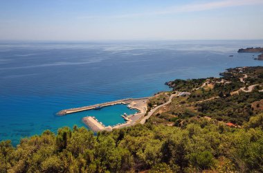 Deniz gemileriyle liman. Körfezdeki sahil ve mimari manzarası - tatil beldesi, turkuaz okyanus suları, Plakias, Girit, Yunanistan