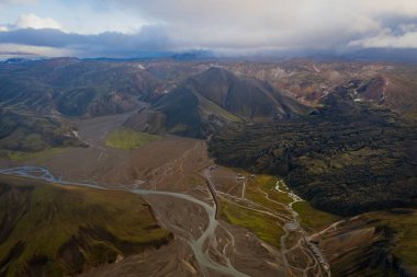 Eylül 2019 'da İzlanda' da. Büyük Vadi Parkı Landmannalaugar. Etrafı rhyolite dağları ve erimemiş karlarla çevrili. Vadide büyük bir kamp inşa edildi. Dünya turları konsepti. Hava aracı görüntüsü.
