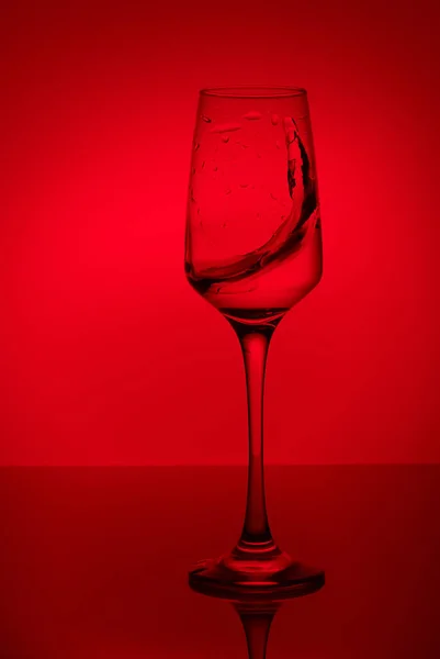 colorful splashes in wineglass on colorful background with colorful water drops