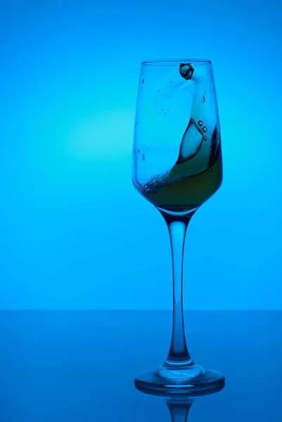 colorful splashes in wineglass on colorful background with colorful water drops