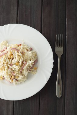 pirzola ve çatal ahşap koyu arka plan üzerinde beyaz bir tabak salata