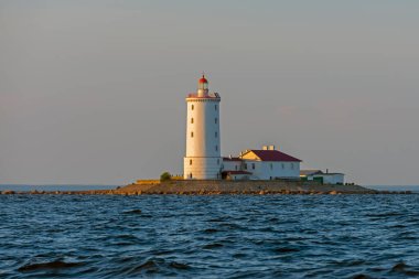 Gün batımında körfezin ortasındaki taş adadaki fener.
