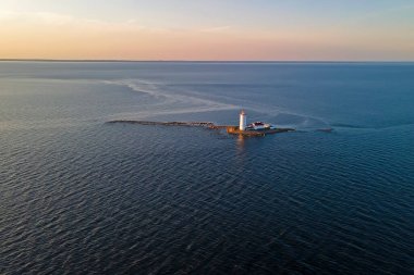 Gün batımında körfezin ortasındaki taş adadaki fener.