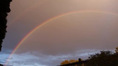 Kenar mahallelerde yağmur yağarken gökkuşağı gökyüzünde beliriyor.