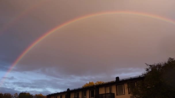 Ein Regenbogen Ragt Den Himmel Während Einem Viertel Stadtrand Nieselt — Stockvideo