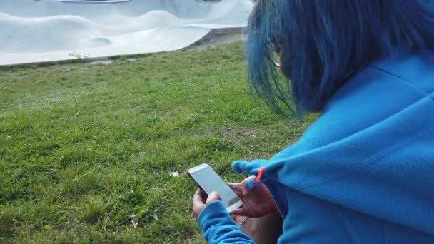 当孩子们玩滑板车时，一个看着她的手机的年轻女人 — 图库视频影像