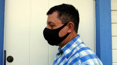 Siyah koruyucu salgın önleyici maskeli bir adamın yüzünü betimleyen renkli bir resim.