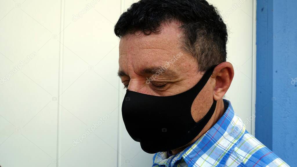 Color image depicting the face of a man with a black protective anti-contagion mask