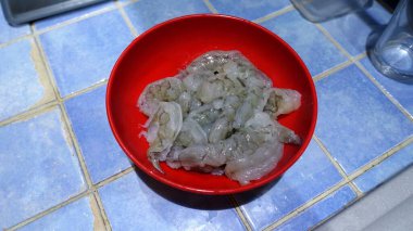 Mutfaktaki kırmızı tabakta pişmeye hazır çiğ karides..