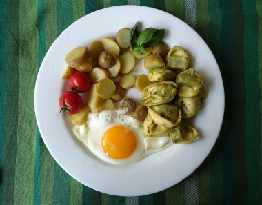 Pesto tortellini soslu tam bir vejetaryen yemeği, kızarmış yumurta, yeni patates salatası, vişneli domates ve fesleğen filizi..