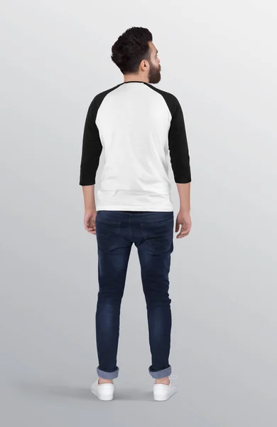 Back profile of standing male model wearing white and black raglan plain shirt in dark blue denim jeans pant on isolated background.