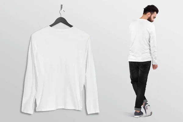 Hanging plain white long sleeve shirt on wall with standing male model. Back view. Isolated background.