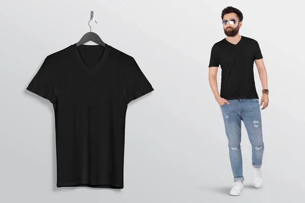 Hanging plain black v neck t shirt on wall beside standing male model. Back view. Isolated background.