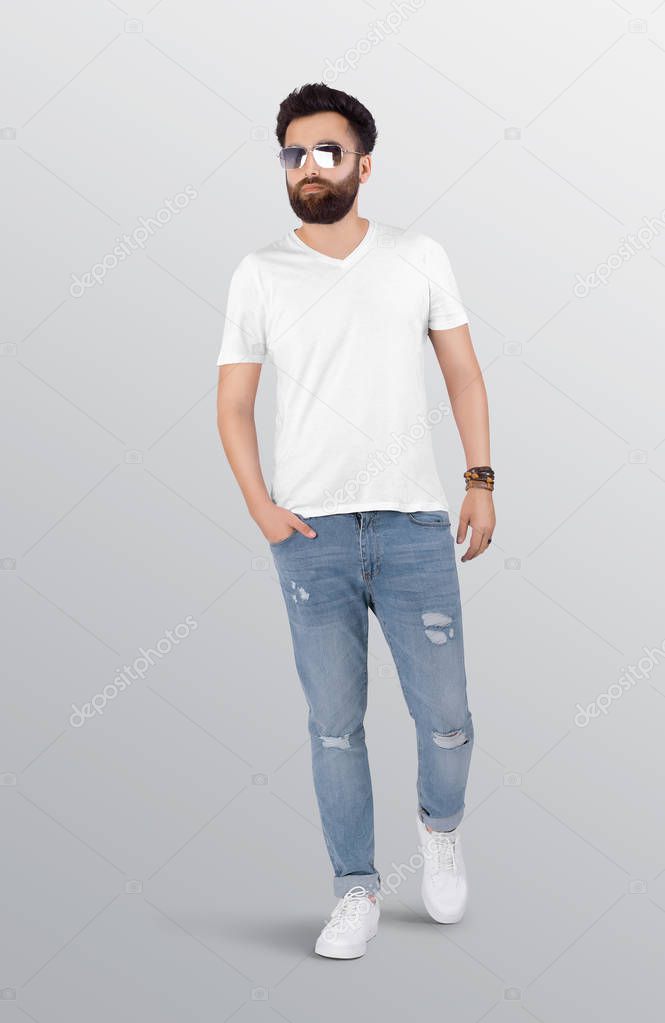Walking male model wearing plain white v neck t shirt in blue ripped denim jeans pant. Isolated background