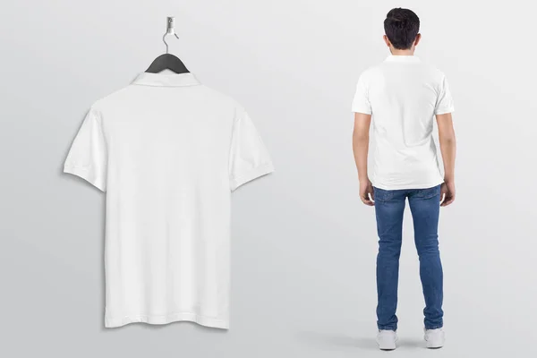 Hanging white plain polo t shirt on wall, with male model in blue denim jeans pant. rear view. Isolated background.