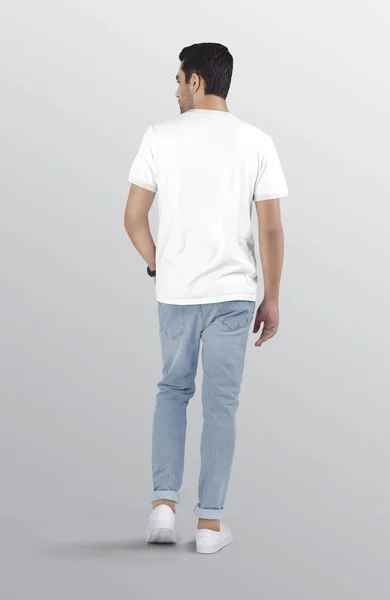 Back view of standing male model wearing white plain t shirt in blue ripped denim jeans pant. Isolated background