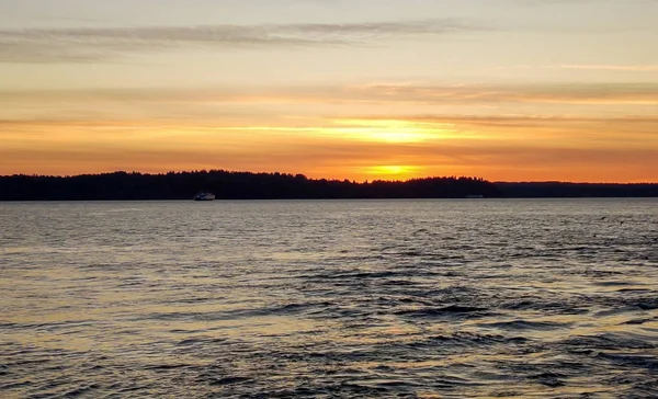 美丽的落日在波涛汹涌的普吉湾水面上 与遥远的瓦松岛和布莱克岛海洋公园相映成趣 还有海鸥和华盛顿州的渡船 — 图库照片