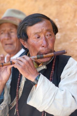Bir flütçü dini bayram sırasında Lhasa sokaklarında hacıları eğlendirir, Tibet