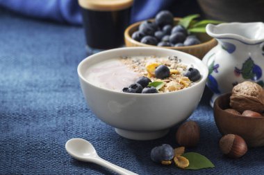 Yoğurt, kahve ve koyu mavi peçete üzerinde çeşitli tahıl taze yaban mersini ile sağlıklı klasik kahvaltı. Metin alanı.