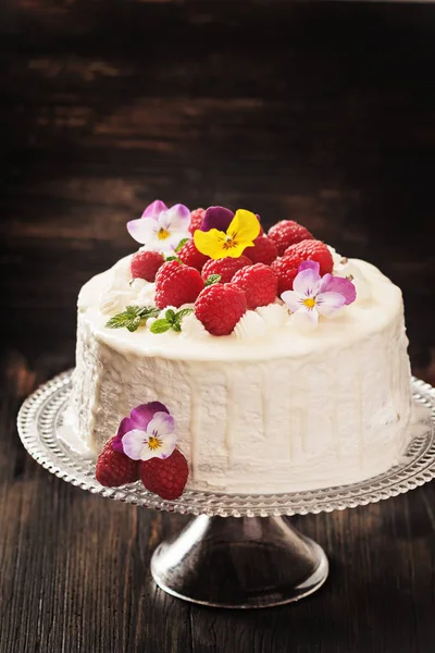 Festive cake with raspberries and flowers with streaks of glaze on  black background