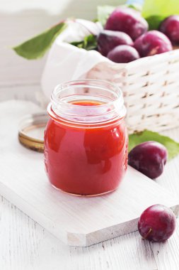 Beyaz ahşap zemin üzerinde bir bardak erik reçeli. Kopya alanı.