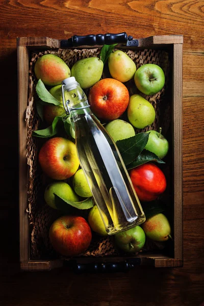 Apple cider vinegar and apples on wooden tray with fruits .