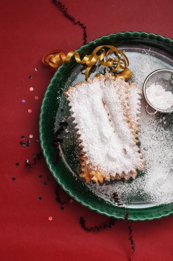 İtalyan Frappe veya chiacchiere - tipik karnaval börek ile tozunu pudra şekeri renkli kırmızı zemin üzerine. Serbest metin alanı ile.