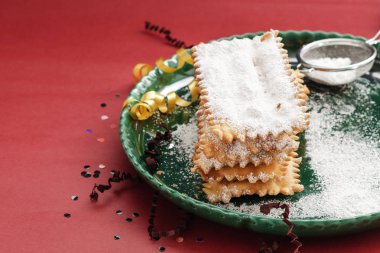 İtalyan Frappe veya chiacchiere - tipik karnaval börek ile tozunu pudra şekeri renkli kırmızı zemin üzerine. Serbest metin alanı ile.