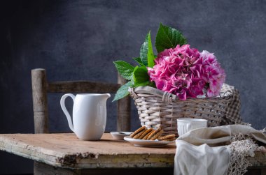 Ahşap masa üzerinde sepet kurabiye ve hortensia çiçek ile rustik tarzına natürmort.
