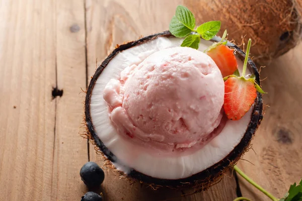 木桌上椰子中的草莓冰淇淋 — 图库照片