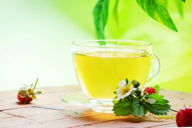 Ahşap masa üzerinde çay ve çilek ile Fincan.