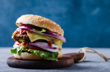 Pirpirit ile geleneksel burger, taze sebze, gri ahşap masada susam ile gevrek topuz.