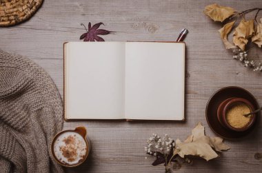 Kırmızı kalem, sonbahar yaprakları, cappuccino ve rahat yün eşarp ile sonbahar mockup eski defter. Düz yatıyordu, üst görünüm.