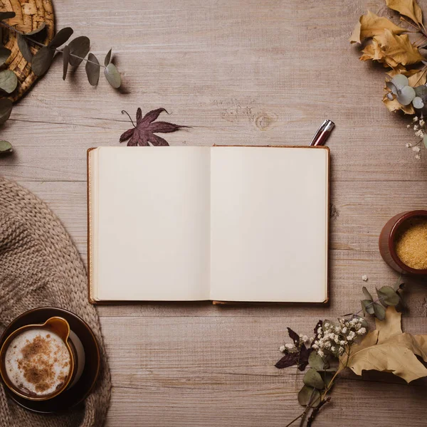 Kırmızı kalem, sonbahar yaprakları, cappuccino ve rahat yün eşarp ile sonbahar mockup eski defter. Düz yatıyordu, üst görünüm.
