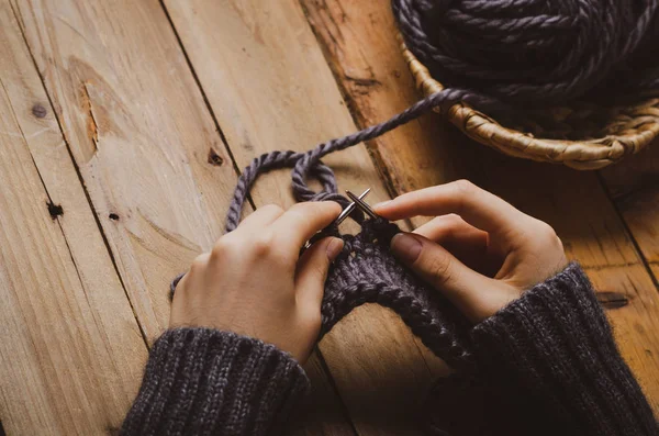 Knitting dark wool with needles. Home hobbies. Cozy comfort concept.