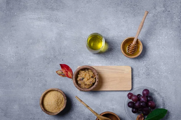 Esmer şekeri üzüm ve yağla ovmak için gerekli malzemeler, cilt bakımı için çevre dostu kozmetik ürünler..