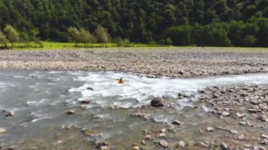 Georgia, Borjomi yakınlarındaki dağ nehrinde rafting yapan kanonun arkasındaki hava uçuşu. Kayakçı, nehrin hızlı akışına rağmen tek bir yerde durarak akıntıya kapılır. İnsansız hava aracı tarafından çekiliyor.