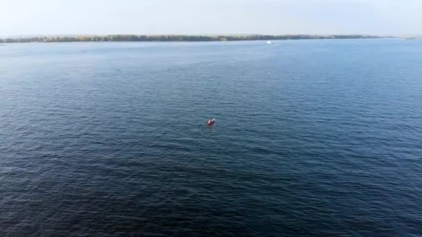 Voo aéreo atrás kayaker, que flutua na superfície da água de grande lago — Vídeo de Stock