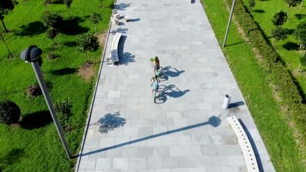 Légi járat a srác és a lány mögött, biciklizés a parkban. A drón elrabolta. — Stock videók