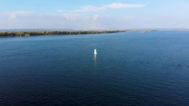 Denizde süzülen yelkenli teknesinin ağaçlık kıyıya doğru kovalamacası. İnsansız hava aracı tarafından çekiliyor.